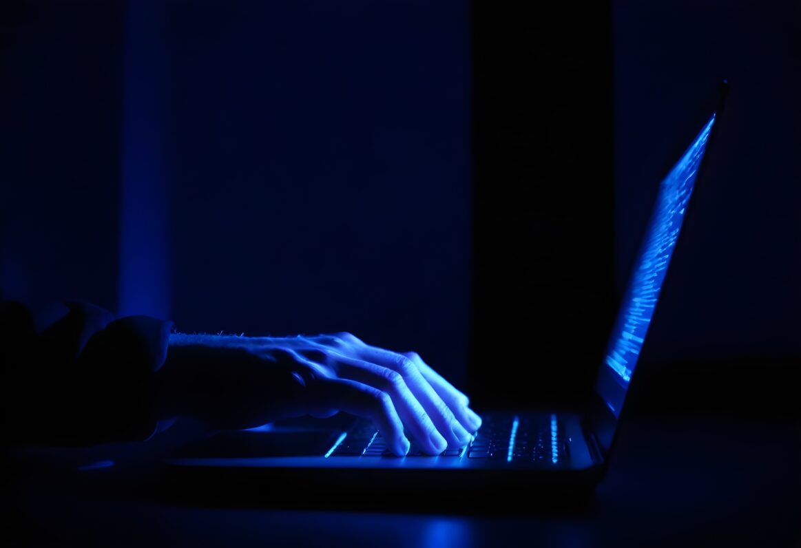 Closeup Persons Hands Typing Laptop Keyboard Illuminated By Screen Dark Room 1 1163x796